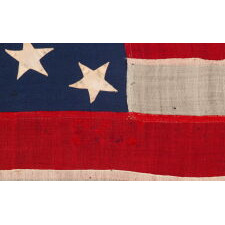 13 STAR ANTIQUE AMERICAN FLAG OF THE CIVIL WAR PERIOD (1861-1865), WITH 9 STRIPES TO REFLECT THE OMISSION OF NORTH & SOUTH CAROLINA, GEORGIA, & VIRGINIA, THE 4 SLAVE STATES AMONG THE ORIGINAL 13 COLONIES THAT SECEDED FROM THE UNION, WITH ITS CANTON RESTING ON THE WAR STRIPE, STRIKING COLOR, AND A BEAUTIFUL MEDALLION CONFIGURATION