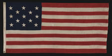 ANTIQUE AMERICAN FLAG WITH 13 STARS IN A 3-2-3-2-3 PATTERN AND AN ELONGATED PROFILE, A SMALL-SCALE FLAG OF THE 1895-1926 ERA