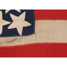 31 STARS ON AN EXTRAORDINARY ANTIQUE AMERICAN FLAG WITH A RANDOM CONSTELLATION, IN VARIOUS SHAPES AND SIZES, CLUSTERED ABOUT AN ENORMOUS CENTER STAR, WITH A COMPLEMENT OF 10 STRIPES; A MASTERPIECE OF EARLY AMERICAN FLAG-MAKING, CALIFORNIA STATEHOOD, 1850-1858