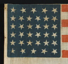 34 STARS, A CIVIL WAR PERIOD PARADE FLAG ON ITS ORIGINAL WOODEN STAFF, RARE AND WITH EXCEPTIONAL GRAPHIC QUALITIES, KANSAS STATEHOOD, 1861-63