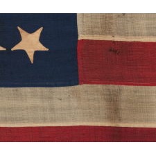 34 UPSIDE-DOWN, HAND-SEWN STARS IN A NOTCHED CONFIGURATION, ON AN ANTIQUE AMERICAN FLAG OF THE CIVIL WAR PERIOD, WITH A BEAUTIFUL AND HIGHLY UNUSUAL JACQUARD WEAVE BINDING, AND IN A TINY SCALE AMONG ITS COUNTERPARTS, REFLECTS THE ADDITION OF KANSAS AS THE 34TH STATE, 1861-1863