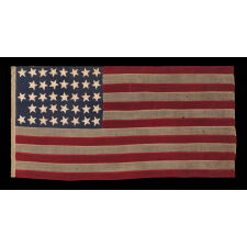 38 STAR ANTIQUE AMERICAN FLAG IN A TINY SCALE AMONG THOSE WITH PIECED-AND-SEWN CONSTRUCTION, WITH A BEAUTIFUL & UNUSUAL SHADE OF BLUE AND WITH A NOTCHED CONFIGURATION OF STARS THAT LEAVES ROOM FOR WESTERN TERRITORIES THAT HAD YET TO BE ADDED; REFLECTS THE PERIOD WHEN COLORADO WAS THE MOST RECENT STATE TO JOIN THE UNION, 1876-1889
