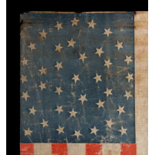 38 STAR ANTIQUE AMERICAN FLAG WITH AN EXCEPTIONALLY RARE “GREAT-STAR-IN-A-WREATH” CONFIGURATION AND ENDEARING WEAR FROM OBVIOUS LONG-TERM USE, 1876-1889, REFLECTS THE ADDITION OF COLORADO TO THE UNION