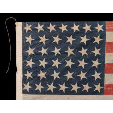 38 STAR ANTIQUE AMERICAN PARADE FLAG IN AN UNUSUALLY LARGE SCALE, WITH ENDEARING WAR FROM OBVIOUS LONG-TERM USE, AND WITH DANCING ROWS IN AN HOURGLASS FORMATION; COLORADO STATEHOOD, 1876-1889