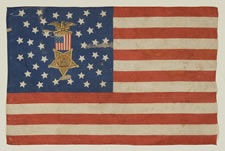 38 STAR FLAG WITH A MULTI-COLOR CIVIL WAR VETERAN'S BADGE AT THE CENTER OF A WHIMSICAL MEDALLION STAR CONFIGURATION AND ITS CANTON RESTING ON THE WAR STRIPE, COLORADO STATEHOOD, 1876-1889
