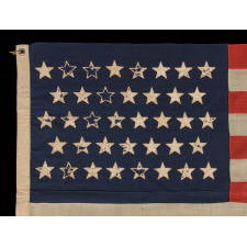 38 STARS WITH ENDEARING WEAR ON AN UNUSUALLY SMALL PIECED-AND SEWN ANTIQUE AMERICAN FLAG OF THE 1876-1889 PERIOD, REFLECTS COLORADO'S ADDITION TO THE UNION