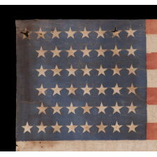 44 STAR ANTIQUE AMERICAN PARADE FLAG WITH ENDEARING WEAR FROM LONG TERM USE AND WITH ITS STARS ARRANGED IN A NOTCHED PATTERN THAT LEAVES 4 SPACES OPEN FOR THE REMAINING WESTERN TERRITORIES, REFLECTS THE PERIOD WHEN WYOMING WAS THE MOST RECENT STATE TO JOIN THE UNION, 1890-1896