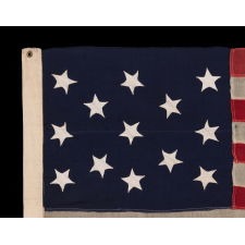 ANTIQUE AMERICAN FLAG WITH 13 HAND-SEWN STARS IN THE 3-2-3-2-3 PATTERN, ORIENTED IN VARIOUS DIRECTIONS ON THEIR VERTICAL AXIS; PROBABLY A U.S. NAVY SMALL BOAT ENSIGN, MADE BETWEEN ROUGHLY 1865 - 1875
