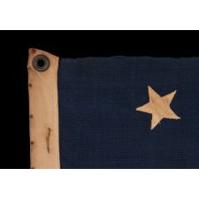 ANTIQUE AMERICAN FLAG WITH 13 HAND-SEWN STARS IN THE 3-2-3-2-3 PATTERN, A U.S. NAVY SMALL BOAT ENSIGN, MADE BETWEEN ROUGHLY 1870 – 1882, WITH ENDEARING WEAR FROM OBVIOUS USE