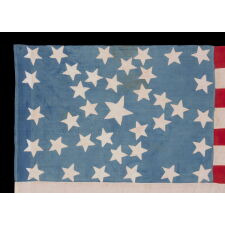 ANTIQUE AMERICAN FLAG WITH 37 STARS ON A CORNFLOWER BLUE CANTON, ARRANGED IN A UNIQUE “GREAT STAR” OR “GREAT LUMINARY” CONFIGURATION, INCORPORATED INTO A RECTANGULAR MEDALLION; A HOMEMADE EXAMPLE, MADE DURING THE ERA OF AMERICAN RECONSTRUCTION; REFLECTS NEBRASKA STATEHOOD, 1867-1876