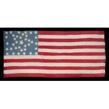 ANTIQUE AMERICAN FLAG WITH 37 STARS ON A CORNFLOWER BLUE CANTON, ARRANGED IN A UNIQUE “GREAT STAR” OR “GREAT LUMINARY” CONFIGURATION, INCORPORATED INTO A RECTANGULAR MEDALLION; A HOMEMADE EXAMPLE, MADE DURING THE ERA OF AMERICAN RECONSTRUCTION; REFLECTS NEBRASKA STATEHOOD, 1867-1876