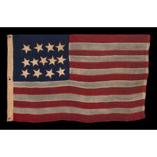 ANTIQUE AMERICAN FLAG WITH A WHIMSICAL PRESENTATION OF 13 STARS IN THE 4-5-4 PATTERN, A VERY EARLY EXAMPLE, MADE circa 1835-1850’s, BOLDY GRAPHIC, ENTIRELY HAND-SEWN AND IN A TINY SCALE AMONG ITS COUNTERPARTS, PROBABLY A U.S. NAVY SMALL BOAT ENSIGN