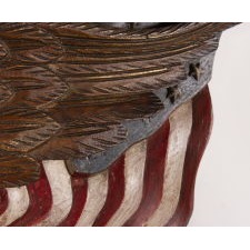 CARVED EAGLE BY GEORGE STAPF, HARRISBURG, PENNSYLVANIA, AN EXCEPTIONAL EXAMPLE WITH TWO OUTSTRETCHED AMERICAN FLAGS AND A FEDERAL SHIELD, ONE OF JUST TWO KNOWN EXAMPLES WITH COMMERCIAL ADVERTISING, MADE CIRCA 1890-WWI