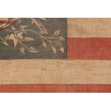 EXTRAORDINARILY RARE ANTIQUE AMERICAN FLAG WITH A THREE-COLOR CANTON THAT CONSISTS OF A TREMENDOUS, WARLIKE EAGLE, PERCHED ON A FEDERAL SHIELD, SET WITHIN A RING OF 14 STARS; MADE IN THE PERIOD BETWEEN THE MEXICAN AND CIVIL WARS (1846 – 1865) THIS IS THE ONLY KNOWN EXAMPLE IN THIS STYLE AND THE LARGEST OF ALL KNOWN RECORDED PARADE FLAGS WITH AN EAGLE AS THE PRIMARY IMAGE