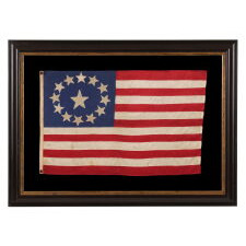 13 STAR ANTIQUE AMERICAN FLAG, MADE OF FINE SILK, WITH AN OVAL VERSION OF WHAT IS KNOWN AS THE 3RD MARYLAND PATTERN AND A LARGE CENTER STAR, IN AN EXTRAORDINARILY TINY SIZE AMONG FLAGS WITH SEWN CONSTRUCTION; FOUND IN WESTERN MASSACHUSETTS, MADE SOMETIME BETWEEN THE 1850’s AND THE CIVIL WAR (1861-65), LIKELY FOR A MILITIA OR VOLUNTEER UNIT, OR AN OFFICER THEREOF; ILLUSTRATED IN “THE STARS & THE STRIPES: FABRIC OF THE AMERICAN SPIRIT” BY RICHARD PIERCE, 2005