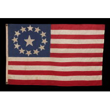13 STAR ANTIQUE AMERICAN FLAG, MADE OF FINE SILK, WITH AN OVAL VERSION OF WHAT IS KNOWN AS THE 3RD MARYLAND PATTERN AND A LARGE CENTER STAR, IN AN EXTRAORDINARILY TINY SIZE AMONG FLAGS WITH SEWN CONSTRUCTION; FOUND IN WESTERN MASSACHUSETTS, MADE SOMETIME BETWEEN THE 1850’s AND THE CIVIL WAR (1861-65), LIKELY FOR A MILITIA OR VOLUNTEER UNIT, OR AN OFFICER THEREOF; ILLUSTRATED IN “THE STARS & THE STRIPES: FABRIC OF THE AMERICAN SPIRIT” BY RICHARD PIERCE, 2005