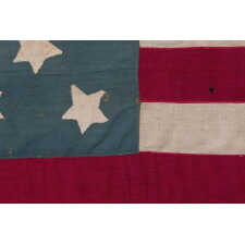 13 STAR ANTIQUE AMERICAN FLAG OF THE CIVIL WAR PERIOD (1861-1865), HOMEMADE AND ENTIRELY HAND-SEWN, WITH ITS CANTON RESTING ON THE WAR STRIPE, AND WITH 9 STRIPES TO REFLECT THE OMISSION OF NORTH & SOUTH CAROLINA, GEORGIA, AND VIRGINIA, THE 4 SLAVE STATES AMONG THE ORIGINAL 13 COLONIES THAT SECEDED FROM THE UNION