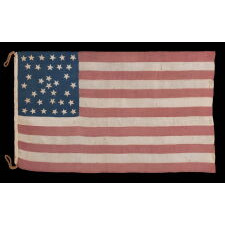 EXTRAORDINARY 34 STAR ANTIQUE AMERICAN FLAG WITH AN ACCORDION OR HOURGLASS MEDALLION CONFIGURATION THAT SURROUNDS A PENTAGON OF STARS IN THE CENTER; MADE OF FINE SILK AND ENTIRELY HAND-SEWN; MADE DURING THE OPENING YEARS OF THE CIVIL WAR (1861-63), IN A TINY SIZE AMONG ITS COUNTERPARTS OF THE PERIOD; REFLECTS THE ADDITION OF KANSAS AS THE 34TH STATE