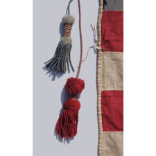 34 STAR ANTIQUE AMERICAN FLAG, MADE DURING THE OPENING TWO YEARS OF THE CIVIL WAR, 1861-1863, WITH AN UNUSUALLY ELONGATED FORMAT, A SQUARE CANTON WITH AN ATTRACTIVE SHADE OF BLUE, LARGE, MAKE-DO TASSELS, AND WITH ITS CANTON RESTING ON A RED STRIPE – SOMETIMES TERMED THE ‘BLOOD’ OR THE ‘WAR’ STRIPE; REFLECTS THE PERIOD WHEN KANSAS WAS THE MOST RECENT STATE TO JOIN THE UNION