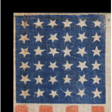 36 STAR ANTIQUE AMERICAN PARADE FLAG, WITH STARS THAT ALTERNATE IN THEIR VERTICAL POSITION FROM COLUMN TO COLUMN AND ROW-TO-ROW, PRINTED ON AN ESPECIALLY INTERESTING LENGTH OF COARSE COTTON WITH A CRUDE WEAVE THAT RESULTS IN A VISUALLY COMPELLING APPEARANCE; CIVIL WAR ERA, NEVADA STATEHOOD, 1864-1867