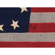13 STARS IN A CRUDE SINGLE WREATH, REMINISCENT OF THE BETSY ROSS PATTERN, THOUGH RENDERED AS MORE OF AN OVAL; ON AN ANTIQUE AMERICAN FLAG MADE & SIGNED BY THE SHOP OF WILLIAM SCHEIBLE, 49 S. 3RD STREET, PHILADELPHIA, APPROX. TWO BLOCKS FROM INDEPENDENCE HALL AND THE SAME FROM THE BETSY ROSS HOUSE; A CIVIL WAR ERA FLAG, WITH AN EXTREMELY RARE & DESIRABLE CONFIGURATION OF STARS FOR THIS PERIOD, CIRCA 1861-65