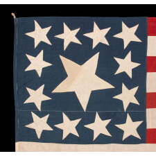 13 STARS IN THE RARE AND VERY DESIRABLE TRUMBULL PATTERN, WITH AN UNUSUALLY ENORMOUS CENTER STAR, ON A HOMEMADE, ANTIQUE AMERICAN FLAG PRODUCED SOMETIME BETWEEN THE CIVIL WAR (1861-1865) & THE 1876 CENTENNIAL OF AMERICAN INDEPENDENCE; THIS STAR CONFIGURATION NAMED FOR ARTIST JOHN TRUMBULL, WHO BRIEFLY SERVED AS GEORGE WASHINGTON’S AIDE-DE-CAMP (1776), BEFORE TRAVELING TO BRITAIN TO TRAIN UNDER WORLD-RENOWNED AMERICAN PAINTER, BENJAMIN WEST, THEN RETURNING TO THE STATES, WHERE HE AFTERWARDS FEA