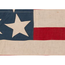 13 STARS IN THE RARE AND VERY DESIRABLE TRUMBULL PATTERN, WITH AN UNUSUALLY ENORMOUS CENTER STAR, ON A HOMEMADE, ANTIQUE AMERICAN FLAG PRODUCED SOMETIME BETWEEN THE CIVIL WAR (1861-1865) & THE 1876 CENTENNIAL OF AMERICAN INDEPENDENCE; THIS STAR CONFIGURATION NAMED FOR ARTIST JOHN TRUMBULL, WHO BRIEFLY SERVED AS GEORGE WASHINGTON’S AIDE-DE-CAMP (1776), BEFORE TRAVELING TO BRITAIN TO TRAIN UNDER WORLD-RENOWNED AMERICAN PAINTER, BENJAMIN WEST, THEN RETURNING TO THE STATES, WHERE HE AFTERWARDS FEA
