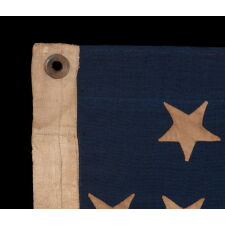 34 UPSIDE-DOWN, HAND-SEWN STARS IN A NOTCHED CONFIGURATION, ON AN ANTIQUE AMERICAN FLAG OF THE CIVIL WAR PERIOD, WITH A BEAUTIFUL AND HIGHLY UNUSUAL JACQUARD WEAVE BINDING, AND IN A TINY SCALE AMONG ITS COUNTERPARTS, REFLECTS THE ADDITION OF KANSAS AS THE 34TH STATE, 1861-1863