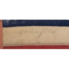 ENTIRELY HAND-SEWN ANTIQUE AMERICAN FLAG OF THE CIVIL WAR ERA, WITH 13 SINGLE-APPLIQUÉD STARS IN A 3-2-3-2-3 CONFIGURATION, IN A GREAT, SMALL SCALE AMONG ITS COUNTERPARTS, PROBABLY MADE IN NEW YORK CITY, SIGNED “GRÜNFILD”