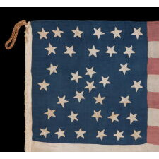 EXTRAORDINARY 34 STAR ANTIQUE AMERICAN FLAG WITH AN ACCORDION OR HOURGLASS MEDALLION CONFIGURATION THAT SURROUNDS A PENTAGON OF STARS IN THE CENTER; MADE OF FINE SILK AND ENTIRELY HAND-SEWN; MADE DURING THE OPENING YEARS OF THE CIVIL WAR (1861-63), IN A TINY SIZE AMONG ITS COUNTERPARTS OF THE PERIOD; REFLECTS THE ADDITION OF KANSAS AS THE 34TH STATE