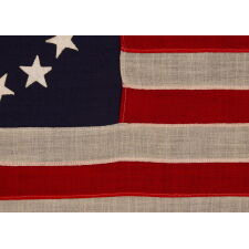 13 STARS IN THE BETSY ROSS PATTERN ON A SMALL-SCALE ANTIQUE AMERICAN FLAG MADE SOMETIME BETWEEN APPROXIMATELY 1910 AND THE 1926 SESQUICENTENNIAL OF AMERICAN INDEPENDENCE