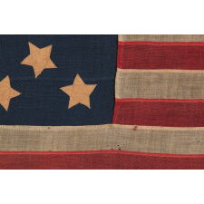 13 STARS WITH SHORT, CONICAL ARMS ON A SMALL SCALE, ANTIQUE AMERICAN FLAG WITH A BEAUTIFULLY ELONGATED FORMAT AND MUCH PATINA FROM OBVIOUS USE; MADE DURING THE LAST DECADE OF THE 19th CENTURY, POSSIBLY BY J.S. OBERHOLTZER IN GERMANTOWN [PHILADELPHIA], PENNSYLVANIA