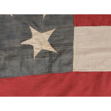 33 HAPHAZARDLY PLACED STARS AND 11 STRIPES ON AN ANTIQUE AMERICAN FLAG WITH ITS CANTON RESTING ON THE WAR STRIPE, POSSIBLY MADE WITH SOUTHERN SYMPATHIES; REFLECTS THE ADDITION OF OREGON TO THE UNION ON VALENTINE’S DAY, 1859; OFFICIAL FROM JULY 4th OF THAT YEAR - JULY 3rd, 1861