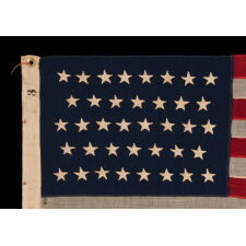 38 HAND-SEWN STARS ON AN ANTIQUE AMERICAN FLAG IN AN EXTRAORDINARILY TINY SCALE AMONG ITS PIECED-AND-SEWN COUNTERPARTS, MADE AT THE TIME WHEN COLORADO WAS THE MOST RECENT STATE TO JOIN THE UNION, 1876-1889; PROBABLY MADE BY THE ANNIN COMPANY IN NEW YORK CITY, SIGNED BY MEMBERS OF THE GRIMES & JOHNSON FAMILIES OF CANANDAIGUA, NEW YORK