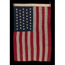 38 HAND-SEWN STARS ON AN ANTIQUE AMERICAN FLAG IN AN EXTRAORDINARILY TINY SCALE AMONG ITS PIECED-AND-SEWN COUNTERPARTS, MADE AT THE TIME WHEN COLORADO WAS THE MOST RECENT STATE TO JOIN THE UNION, 1876-1889; PROBABLY MADE BY THE ANNIN COMPANY IN NEW YORK CITY, SIGNED BY MEMBERS OF THE GRIMES & JOHNSON FAMILIES OF CANANDAIGUA, NEW YORK