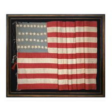 34 STARS ON AN EARLY CIVIL WAR FLAG (1861-1863) WITH ITS CANTON RESTING ON THE WAR STRIPE, AN UNUSUAL ELONGATED FORM; AN ATTRACTIVE SHADE OF BLUE, AND LARGE, MAKE-DO TASSELS, KANSAS STATEHOOD