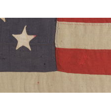 13 STARS ARRANGED IN A 3-2-3-2-3 PATTERN ON A BEAUTIFUL DUSTY BLUE CANTON, ON A SMALL-SCALE ANTIQUE AMERICAN FLAG MADE BETWEEN THE MID-1880'S AND 1890'S