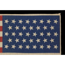 38 STARS IN A LINEAL ARRANGEMENT THAT IS COMPRISED OF JUST 5 ROWS OF CANTED STARS, UNUSUAL FOR A PARADE FLAG IN THIS STAR COUNT, PROBABLY MADE FOR THE CENTENNIAL INTERNATIONAL EXHIBITION IN PHILADELPHIA IN 1876, THIS STAR COUNT REFLECTING COLORADO STATEHOOD