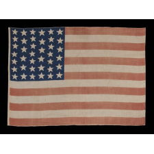 39 STARS IN TWO SIZES, ALTERNATING FROM ONE COLUMN TO THE NEXT, ON AN ANTIQUE AMERICAN PARADE FLAG DATING TO THE 1876 CENTENNIAL, NEVER AN OFFICIAL STAR COUNT, REFLECTS THE ANTICIPATED ARRIVAL OF THE DAKOTA TERRITORY