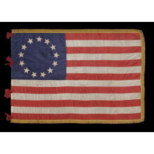 BEAUTIFULLY GRAPHIC AND HIGHLY UNORDINARY 13 STAR FLAG IN THE BETSY ROSS PATTERN, A MADE OF FINE SILK WITH SILK FRINGE AND TIES, IN A TINY SIZE AMONG ITS COUNTERPARTS CA 1895-1926