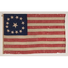 13 STAR ANTIQUE AMERICAN FLAG WITH A CIRCULAR VERSION OF WHAT IS KNOWN AS THE 3RD MARYLAND PATTERN, ENTIRELY HAND-SEWN, WITH ESPECIALLY LARGE STARS SURROUNDING AN EVEN LARGER CENTER STAR; MADE SOMETIME BETWEEN 1850 AND THE CIVIL WAR (1861-65), AN EXCEPTIONAL EXAMPLE WITH WONDERFUL FOLK QUALITIES