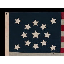 13 SLIGHTLY BULBOUS STARS IN A MEDALLION CONFIGURATION, WITH A LARGE CENTER STAR, ON A SMALL-SCALE ANTIQUE AMERICAN FLAG MADE DURING THE LAST DECADE OF THE 19TH CENTURY, CA 1890-1895