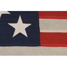 13 STAR ANTIQUE AMERICAN FLAG, A U.S. NAVY SMALL BOAT ENSIGN WITH ENORMOUS HAND-SEWN STARS, IN A REMARKABLE STATE OF PRESERVATION, MADE CA 1890-1899