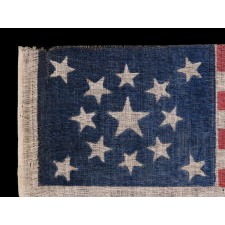 13 STARS IN A MEDALLION PATTERN ON AN ANTIQUE AMERICAN PARADE FLAG MADE FOR THE 1876 CENTENNIAL CELEBRATION; A LARGE EXAMPLE AMONG ITS COUNTERPARTS OF THE PERIOD