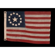 13 STAR ANTIQUE AMERICAN FLAG, IN A TINY SCALE AMONG PIECED-AND-SEWN EXAMPLES OF THE 19TH CENTURY, WITH HAND-SEWN STARS ARRANGED IN A CIRCULAR VERSION OF WHAT IS KNOWN AS THE 3RD MARYLAND PATTERN; FEATURES AN ESPECIALLY LARGE CENTER STAR, MADE circa 1890