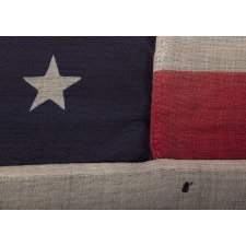 38 STARS IN A NOTCHED, CROSSHATCH PATTERN ON AN ANTIQUE AMERICAN FLAG MADE BY THE U.S. BUNTING COMPANY IN LOWELL, MASSACHUSETTS, SIGNED "TORREY," REFLECTS THE ERA OF COLORADO STATEHOOD, CIRCA 1876-1889