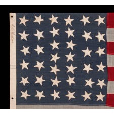 38 STARS IN CRUDE COLUMNS WITH HAPHAZARD ORIENTATION, ON AN ANTIQUE AMERICAN FLAG WITH A BEAUTIFUL, SLATE BLUE CANTON, SIGNED "LEDDON," MADE IN THE ERA WHEN COLORADO WAS THE MOST RECENT STATE TO JOIN THE UNION, 1876-1889