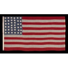 38 STARS IN CRUDE COLUMNS WITH HAPHAZARD ORIENTATION, ON AN ANTIQUE AMERICAN FLAG WITH A BEAUTIFUL, SLATE BLUE CANTON, SIGNED "LEDDON," MADE IN THE ERA WHEN COLORADO WAS THE MOST RECENT STATE TO JOIN THE UNION, 1876-1889