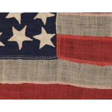 34 HAPHAZARDLY PLACED, HAND-SEWN STARS, IN CRUDE LINEAL ROWS, ON AN ANTIQUE AMERICAN FLAG OF THE CIVIL WAR PERIOD WITH HAND-SEWN STRIPES AND IN A TINY SCALE AMONG ITS COUNTERPARTS, 1861-1863, REFLECTS THE ADDITION OF KANSAS AS THE 34TH STATE