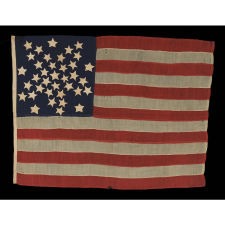 37 STARS IN A WHIMSICAL REPRESENTATION OF THE "GREAT STAR" PATTERN WITH A STAR BETWEEN EACH ARM, ON A HAND-SEWN FLAG IN A REMARKABLY TINY SCALE FOR THE PERIOD, PROBABLY 1867-1876, NEBRASKA STATEHOOD, AN EXCEPTIONAL EXAMPLE